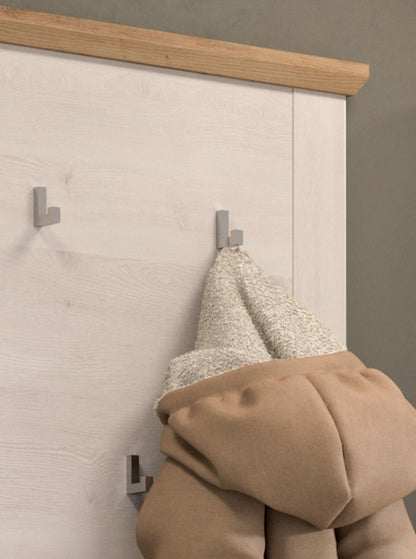 Garderobenpaneel mit Metallhaken; Mantel am Haken auf weißem Holzdekor mit brauner Leiste.