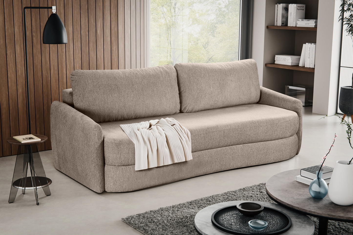 Schlafsofa in beigem Stoff mit zwei Rückenkissen und ausgebreitetem Tuch