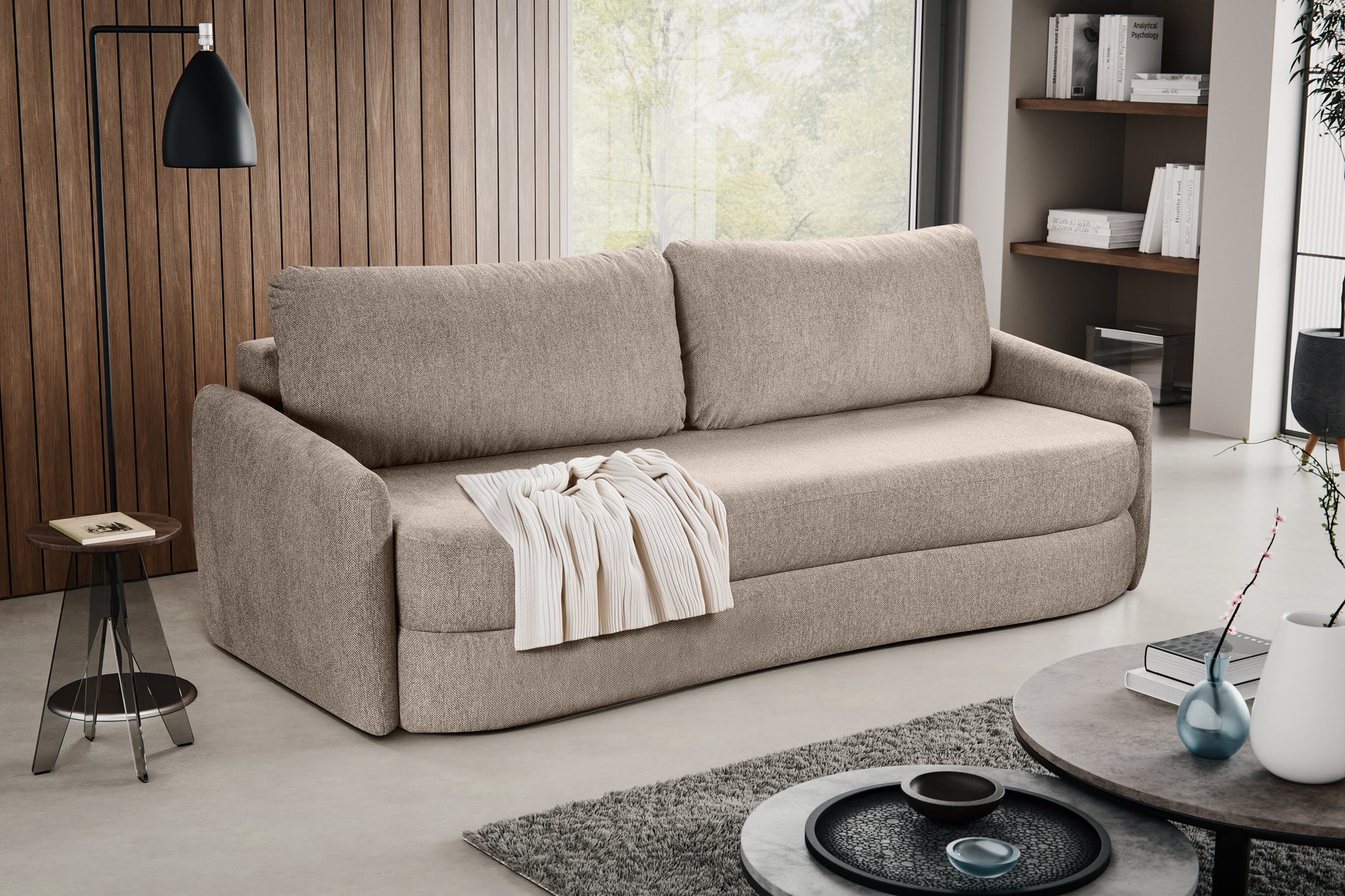 Schlafsofa in beigem Stoff mit zwei Rückenkissen und ausgebreitetem Tuch