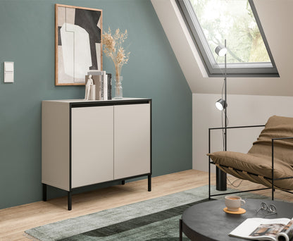 Kommode mit zwei Türen, hellgrau, schwarze Füße, im Wohnraum neben Sofa