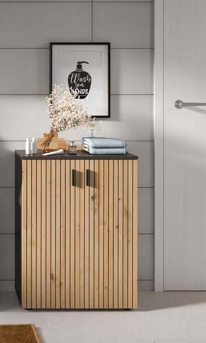 Badschrank mit Holzlamellen und dunkler Oberplatte, zwei Türen mit schwarzen Griffen