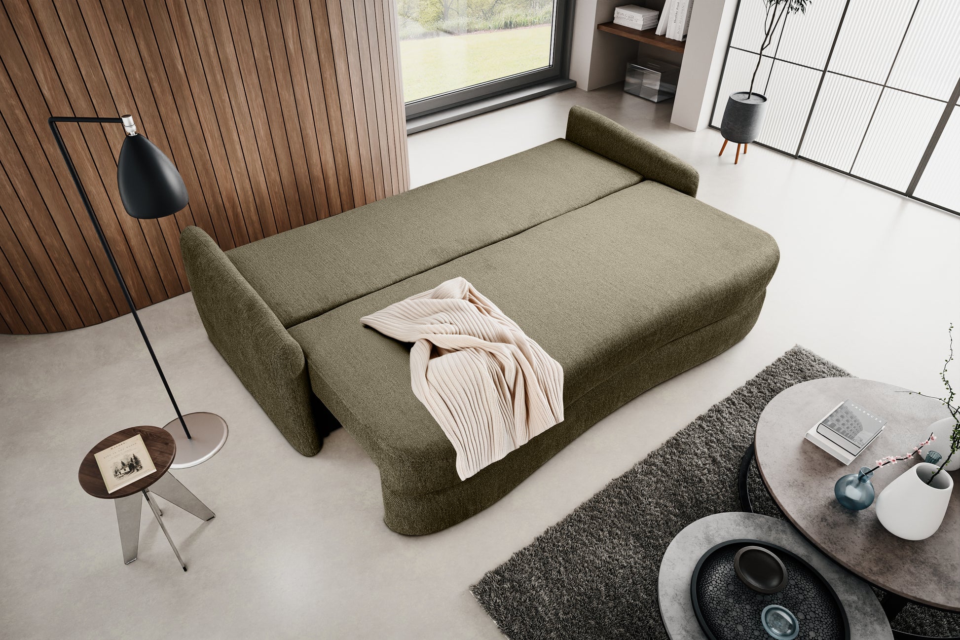 Schlafsofa mit ausgeklappter Liegefläche, olivgrünem Polster und gerollter Decke